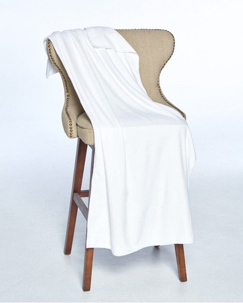 May include: A white throw blanket draped over a wooden chair with a beige fabric seat. The chair has a decorative nailhead trim.