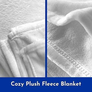 May include: Close-up of a white plush fleece blanket showing the soft texture and stitching. The blanket is folded in half, revealing the inside of the fabric.
