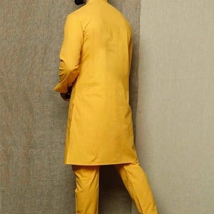 May include: A yellow kurta and matching pants set. The kurta has a mandarin collar and long sleeves. The pants are straight-leg and have a relaxed fit.