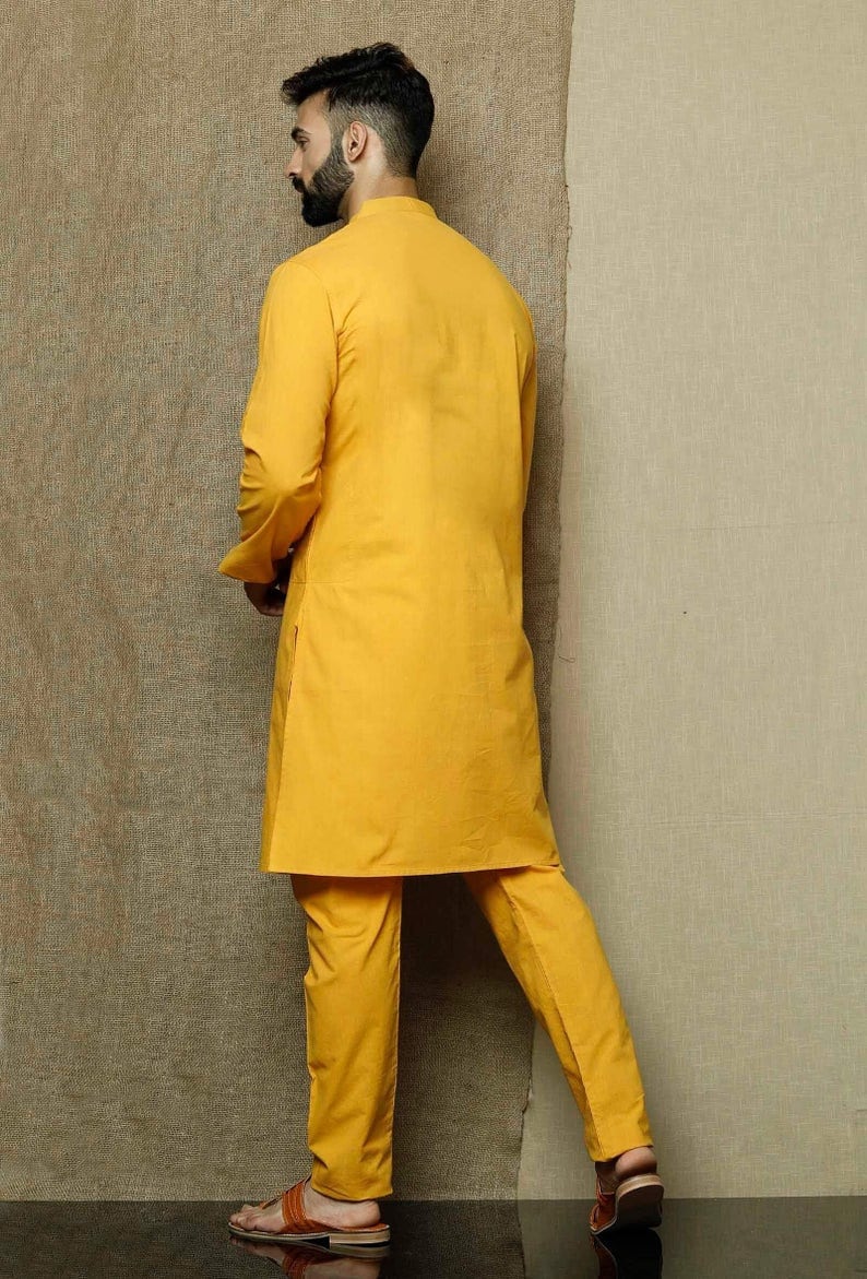 May include: A yellow kurta and matching pants set. The kurta has a mandarin collar and long sleeves. The pants are straight-leg and have a relaxed fit.