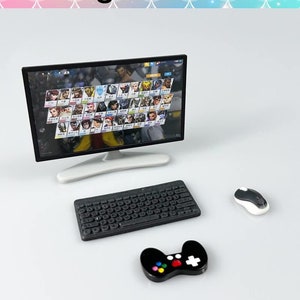 May include: A miniature computer setup with a black computer monitor, a black keyboard, a black and white video game controller, and a white mouse. The monitor displays a video game screen with multiple characters.