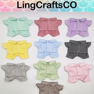 May include: Ten pairs of gingham pajamas in various colors, including green, red, purple, yellow, blue, black, gray, light green, pink, and brown. The pajamas have a button-up shirt and shorts.