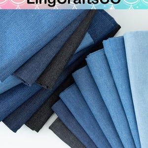 May include: A collection of folded fabric swatches arranged in a fan pattern, displaying a gradient of blue and black shades. The stack includes various textures of denim-like material, ranging from light sky blue to deep navy and solid black.
