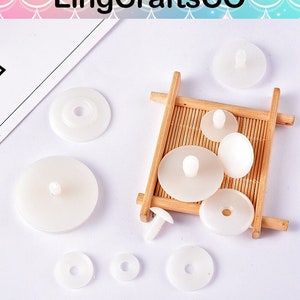 May include: Assortment of white plastic buttons in a variety of sizes and shapes. Some buttons have a small post on the top.