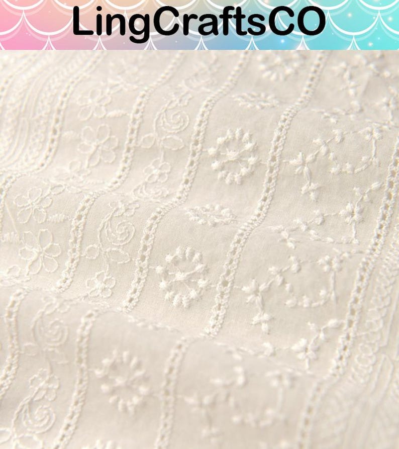 May include: Off-white fabric featuring vertical stripes of intricate white floral embroidery and delicate eyelet detailing. The textile displays a repeating pattern of small blossoms and vines, creating a textured surface with a consistent, repeating design.