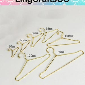 May include: A collection of gold-colored metal wire hangers in various sizes, ranging from 40mm to 150mm. The hangers are displayed against a light background, showcasing their simple design and varying lengths.
