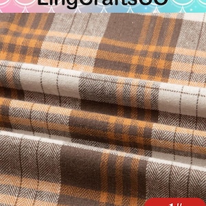 May include: A fabric featuring a plaid pattern in shades of brown, mustard yellow, and off-white. The textile displays a visible herringbone weave texture throughout the design, with the fabric folded to create soft, horizontal pleats across the surface.