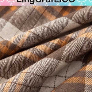May include: A fabric with a plaid pattern in shades of brown, tan, and orange. The material features a visible herringbone weave texture throughout the design, with thin dark brown lines intersecting to form a grid across the checkered surface.