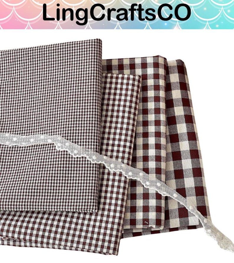 May include: Four folded fabric squares featuring various sizes of brown and white gingham check patterns, layered together. A thin, white, scalloped lace trim with small, evenly spaced white dots is draped diagonally across the fabric stack.