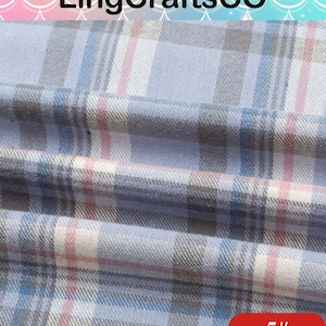 May include: A woven fabric featuring a plaid pattern in shades of light blue, white, grey, and thin pink stripes. The material is folded, creating soft horizontal drapes across the surface. The text LingCraftsCO appears at the top, and 5# is at the bottom.