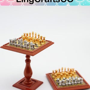 May include: Miniature chess set with gold and silver pieces on a brown wooden chessboard. One set is on a small, matching table, and the other is on a flat surface. The chessboards have a classic black and gold checkered pattern.