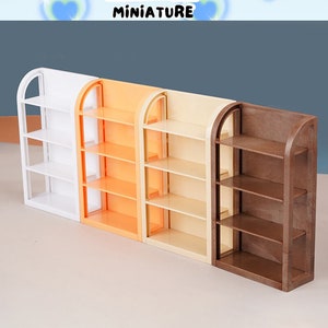 May include: Four miniature wooden shelves in white, orange, beige, and brown. The shelves are all the same size and have four shelves each. The shelves are arranged in a row from left to right. The text "STONE TOWER MINIATURE" is at the top of the image.