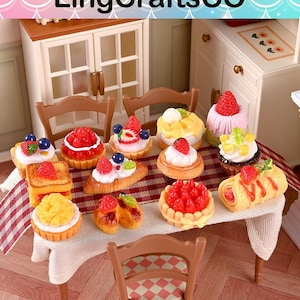 May include: A miniature table set with various pastries, including tarts, croissants, and rolls, all topped with fresh strawberries, blueberries, and cream. The table is set with a white tablecloth and two miniature chairs. The text "LingCraftsCO" is at the top.