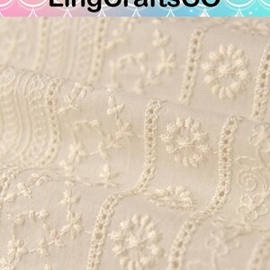 May include: Off-white fabric featuring vertical stripes of intricate white floral and geometric embroidery. The textile displays a repeating pattern of small blossoms, vines, and circular motifs. The text LingCraftsCO is visible at the top.