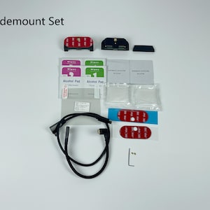 Peut inclure: Un ensemble Slidemount, comprenant des composants rouges et noirs, des tampons imbibés d'alcool, des lingettes et un câble noir. L'ensemble contient également des tampons adhésifs et de petites pièces métalliques. Le texte "Slidemount Set" est visible.