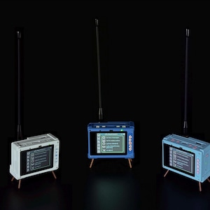 Può includere: Tre dispositivi elettronici rettangolari con antenne, ciascuno dotato di uno schermo digitale che mostra un elenco di menu, pulsanti di controllo laterali e due gambe sottili. I dispositivi sono bianchi, blu scuro e azzurro su sfondo nero.