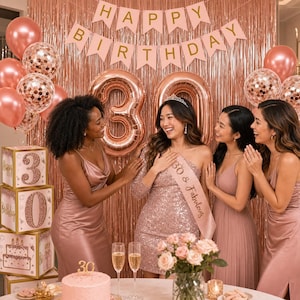 May include: A group of women celebrating a 30th birthday. The scene includes rose gold balloons, a banner that says "Happy Birthday", and a cake. The birthday girl wears a sash that says "30 & Fabulous".