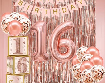 May include: A rose gold birthday party decoration set. Includes a large number 16 balloon, balloons, a banner that says "Happy Birthday", and decorative boxes with the numbers 1 and 6. The background is a rose gold fringe curtain.