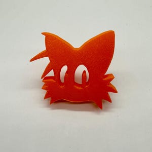 May include: Orange 3D printed figurine of a cartoon fox with large eyes and a bushy tail.