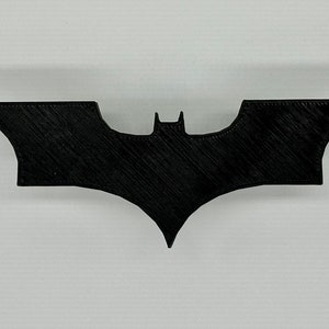 May include: Black Batman logo silhouette, a popular superhero symbol.