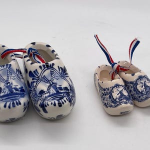 May include: A white ceramic mug with a black handle and the text "But First, Coffee" in a bold, black font. The mug is set against a blurred background, suggesting a cozy setting.