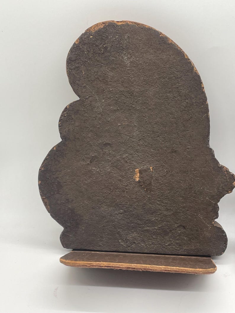 May include: A pair of brown bookends with a textured, dark brown surface. The bookends have a decorative, curved shape and sit on a rectangular base. The edges of the bookends have a lighter brown color.