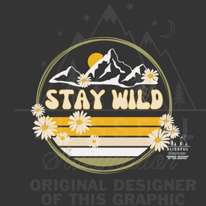 May include: A yellow and white graphic design with a mountain range and a sun in a circle. The text "STAY WILD" is in a retro font. The design is surrounded by white daisies.