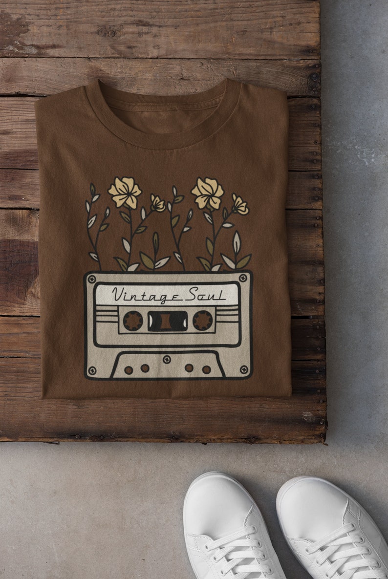 May include: A brown t-shirt with a vintage cassette tape design and the text "Vintage Soul" printed on it. The cassette tape is surrounded by stylized flowers.