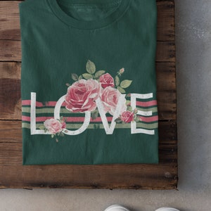 May include: A green t-shirt with a white "LOVE" graphic and pink roses. The graphic is layered over pink and green stripes.