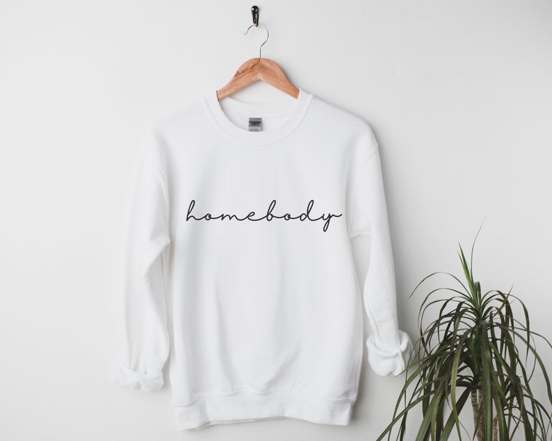 May include: White sweatshirt with the text "homebody" written in black cursive script.
