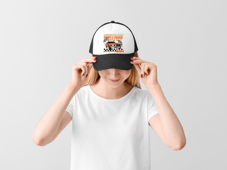 a woman wearing a trucker style hat with the vintage racing club design. the retro design features a orange muscle car with checkered racing flags.  the words vintage racing club above and the words life in the fast lane 1984 below.