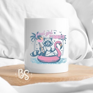 May include: White ceramic mug with a graphic of a raccoon wearing a pink flamingo float and holding a bottle of beer. The text "feral girl summer" is printed on the mug.