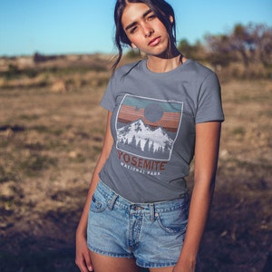 May include: A grey t-shirt with a vintage-style graphic of a mountain range and a sun with the text "Yosemite National Park".