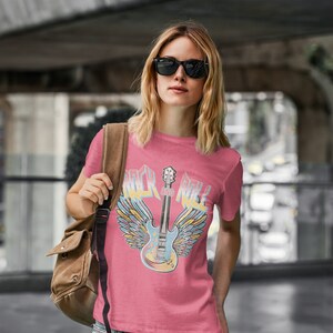May include: A pink t-shirt featuring a graphic of a guitar with wings and the text "Rock and Roll".