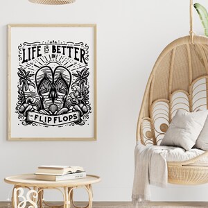 May include: Black and white illustration of flip flops with the text "Life is better in flip flops". The illustration is framed and hanging on a white wall. A wicker hanging chair with a white throw blanket is in the foreground.