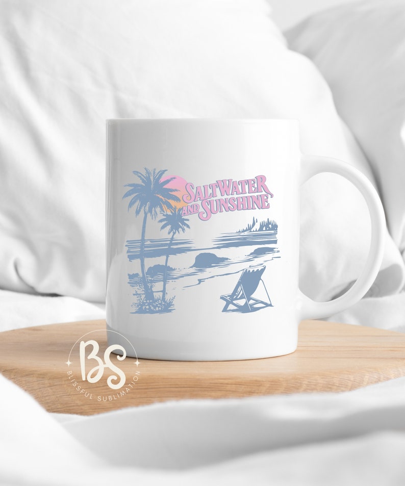May include: White ceramic mug with a blue and pink design of palm trees, a beach scene, and the text "Saltwater and Sunshine".
