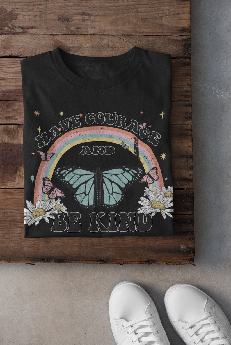 May include: Black t-shirt with a rainbow and butterfly graphic. The text "Have Courage and Be Kind" is printed on the shirt.