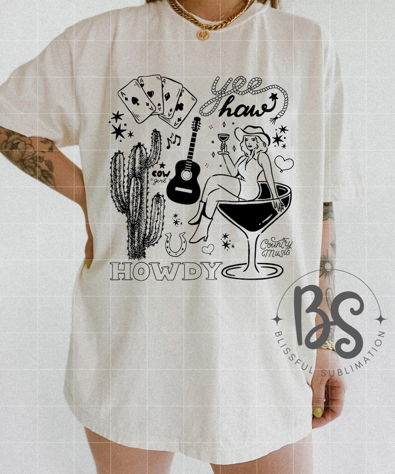 Pode incluir: Uma camiseta branca com um design gr&aacute;fico preto que apresenta uma vaqueira com um chap&eacute;u de vaqueiro, segurando uma ta&ccedil;a de vinho, sentada em uma ta&ccedil;a de martini. O design tamb&eacute;m inclui um cacto, uma ferradura, cartas de jogo, um viol&atilde;o, notas musicais e o texto "Yee haw" e "Howdy".