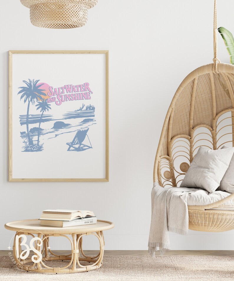 May include: A framed print with a blue and pink illustration of a beach scene with palm trees, a sunset, and a beach chair. The text "Saltwater and Sunshine" is written in pink on the print.