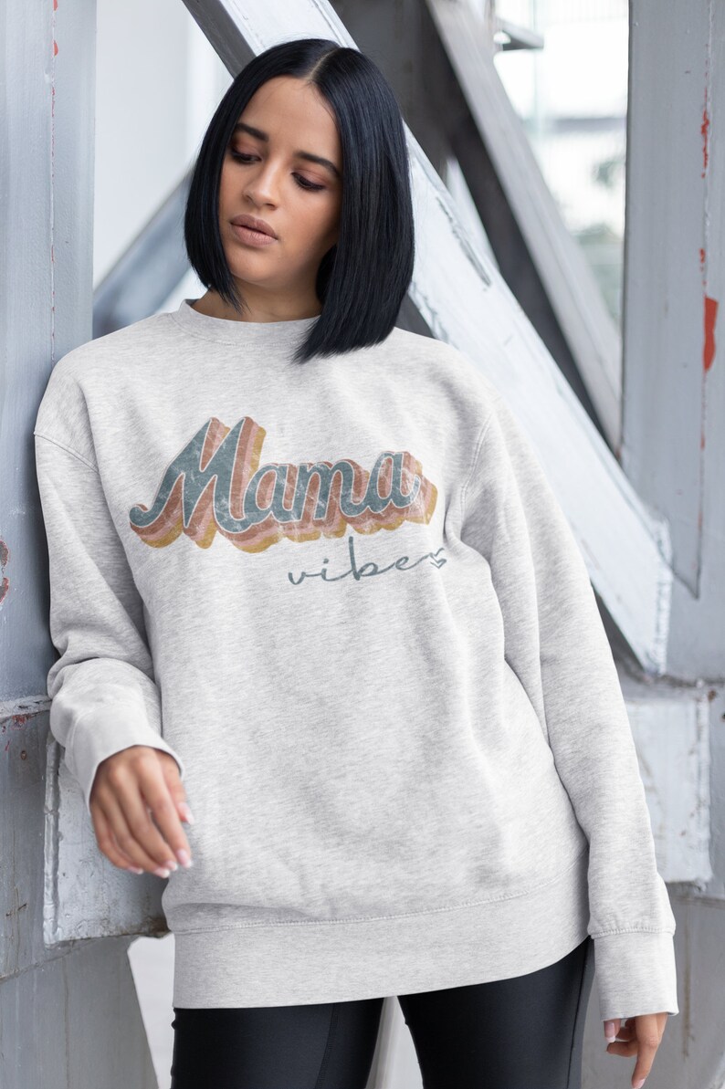 Puede incluir: Una sudadera gris con el texto "Mama Vibes" en una fuente retro arco&iacute;ris.
