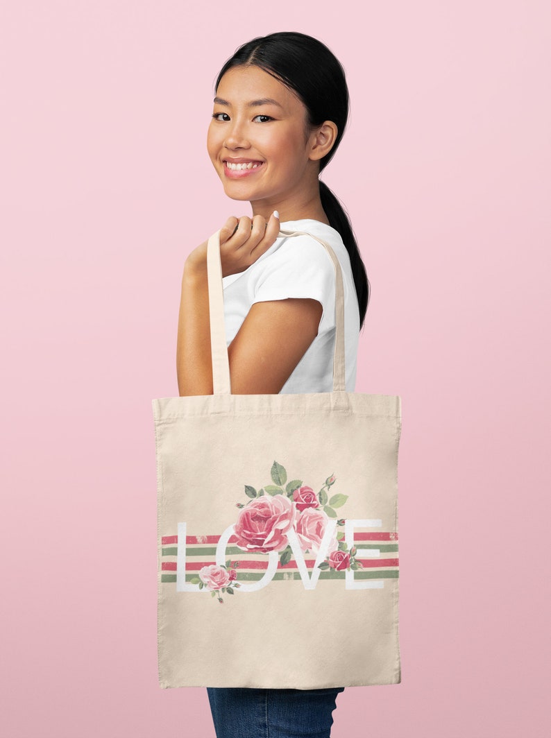 May include: A beige tote bag with a floral design and the word "LOVE" printed in white. The bag has green and pink stripes.