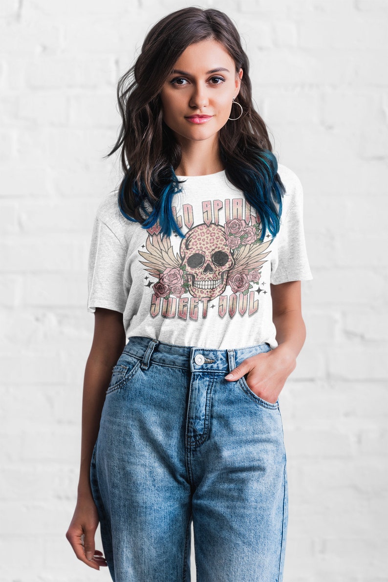 May include: White t-shirt with a graphic of a pink and black leopard print skull with wings and flowers. The text "Wild Spirit Sweet Soul" is printed below the skull.