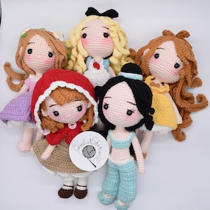 May include: Five crocheted dolls with different colored dresses and hair. The dolls are all smiling and have large eyes. The dolls are sitting on a white surface. The dolls are all wearing different outfits. The dolls are all handmade. The dolls are all unique. The dolls are all beautiful. The dolls are all perfect for a child's playroom. The dolls are all perfect for a collector. The dolls are all perfect for a gift. The dolls are all perfect for a special occasion.