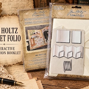 May include: A Tim Holtz idea-ology Pocket Folio interactive accordion booklet in clear plastic packaging. The packaging features the product name, brand logo, and illustrations of the folded paper structure and an example of a completed project.