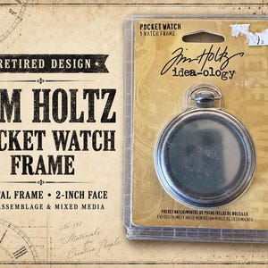 May include: A Tim Holtz Idea-ology pocket watch frame in a clear plastic blister pack. The packaging features tan cardstock with black text reading Pocket Watch, 1 Watch Frame, and 2-inch face. The metal frame is circular with a top loop.