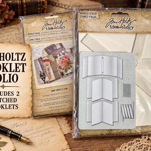 May include: A Tim Holtz Idea-ology Booklet Folio in clear plastic packaging. The product includes a cream-colored folder with a fabric tie and two stitched booklets. The packaging features the text Tim Holtz idea-ology and Booklet Folio.