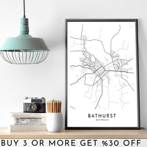 Puede incluir: Impresión de mapa de arte de línea en blanco y negro de Bathurst, Australia. La impresión está enmarcada en un marco negro y está colgada en una pared blanca. La impresión está en un estante con una cámara, lápices y libros.