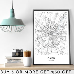 Può includere: Una stampa di mappa in bianco e nero di Caen, Francia, in una cornice bianca. La mappa mostra le strade e le vie d'acqua della città. Il testo "CAEN FRANCE" è stampato sotto la mappa.