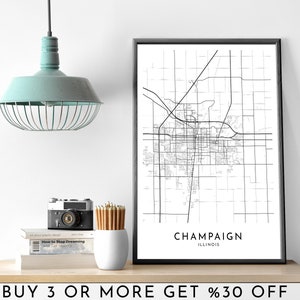 May include: Black and white line art map print of Champaign, Illinois. The print is framed in a black frame and is hanging on a white wall. The print is on a shelf with a camera, pencils, and books.