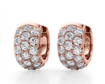 May include: A pair of rose gold hoop earrings encrusted with numerous round, clear gemstones. The earrings have a curved, chunky design, with the gemstones covering the front and sides of the hoops. The background is plain white.